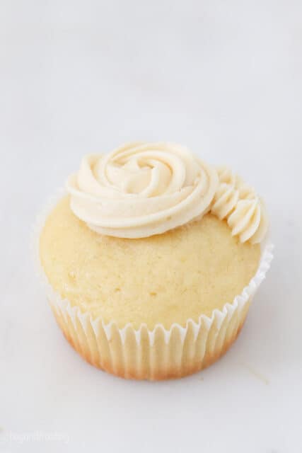 a half frosted vanilla cupcake on a marble background