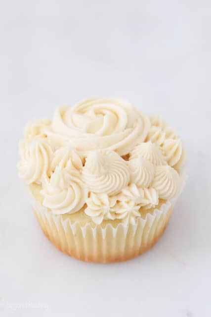 a frosted vanilla cupcake on a marble background