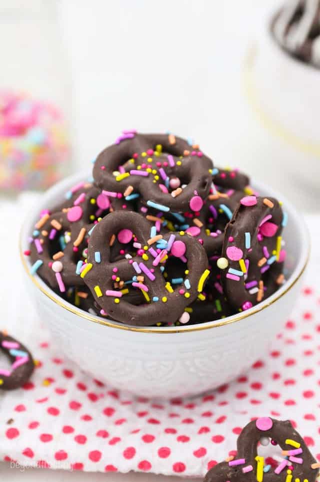 Mini pretzel twists covered in chocolate with blue pink and yellow sprinkles