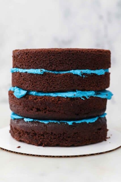 a four tiered chocolate cake stacked with blue frosting between the layers