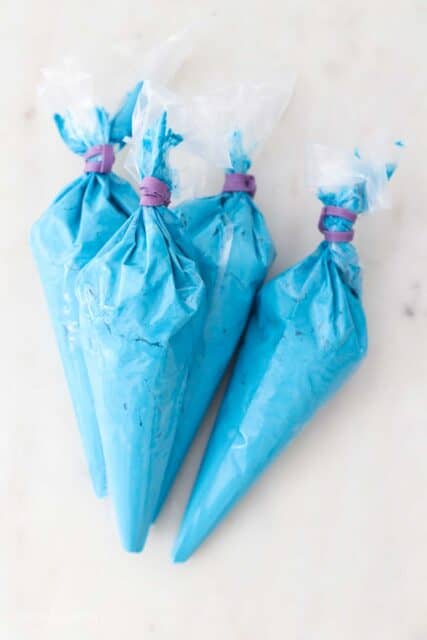 four piping bags filled with blue frosting