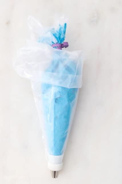 a piping bag filled with blue frosting inside a second piping bag