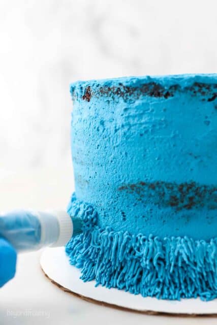a close up of a piping bag with blue frosting on a cake