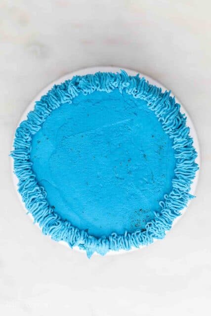 a frosted cookie monster cake showing how to frosting the top of the cake
