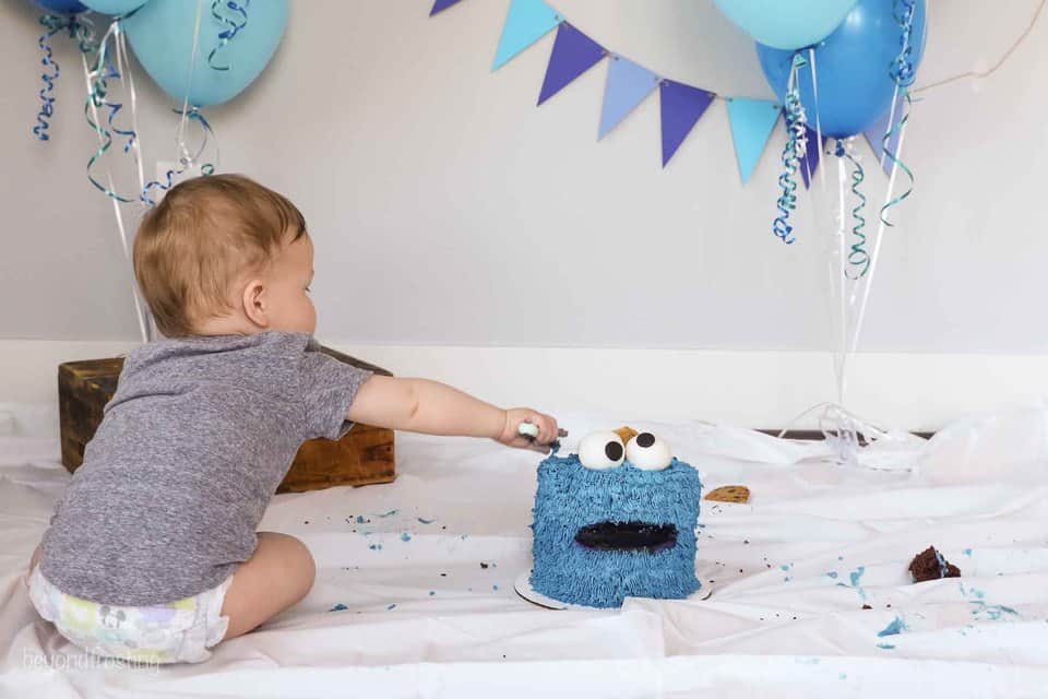 a baby putting his hands into a cookie monster cake