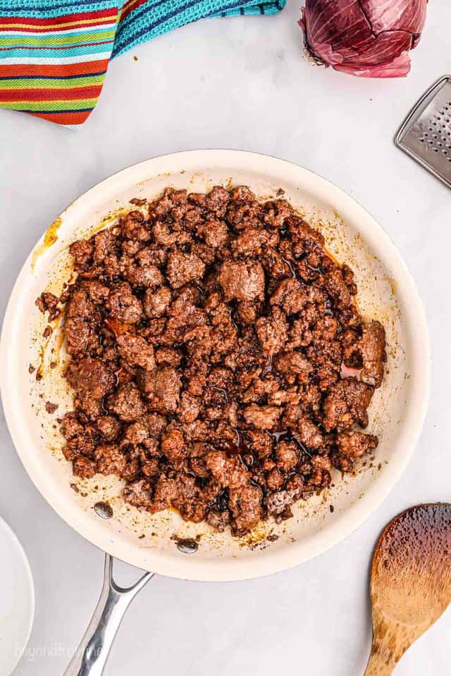 Ground beef cooking in a pan with seasoning