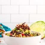 A big bowl of taco salad piled with veggies, tortillas, avocado and ground beef