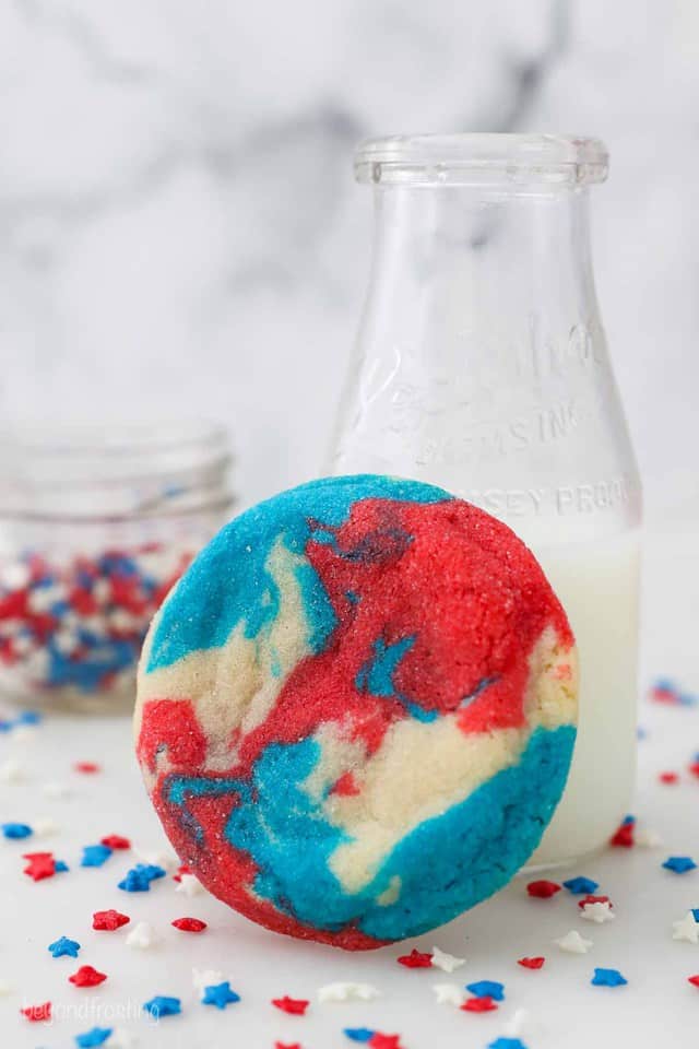 A tye dye cookie leaning up against a milk jar