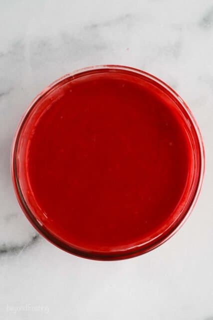 overhead shot of red cake batter in a glass bowl