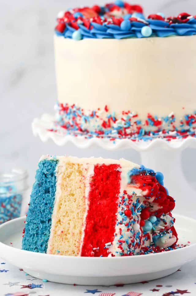 a slice of 3 layer cake with layers of blue, white and red cake o a white plate