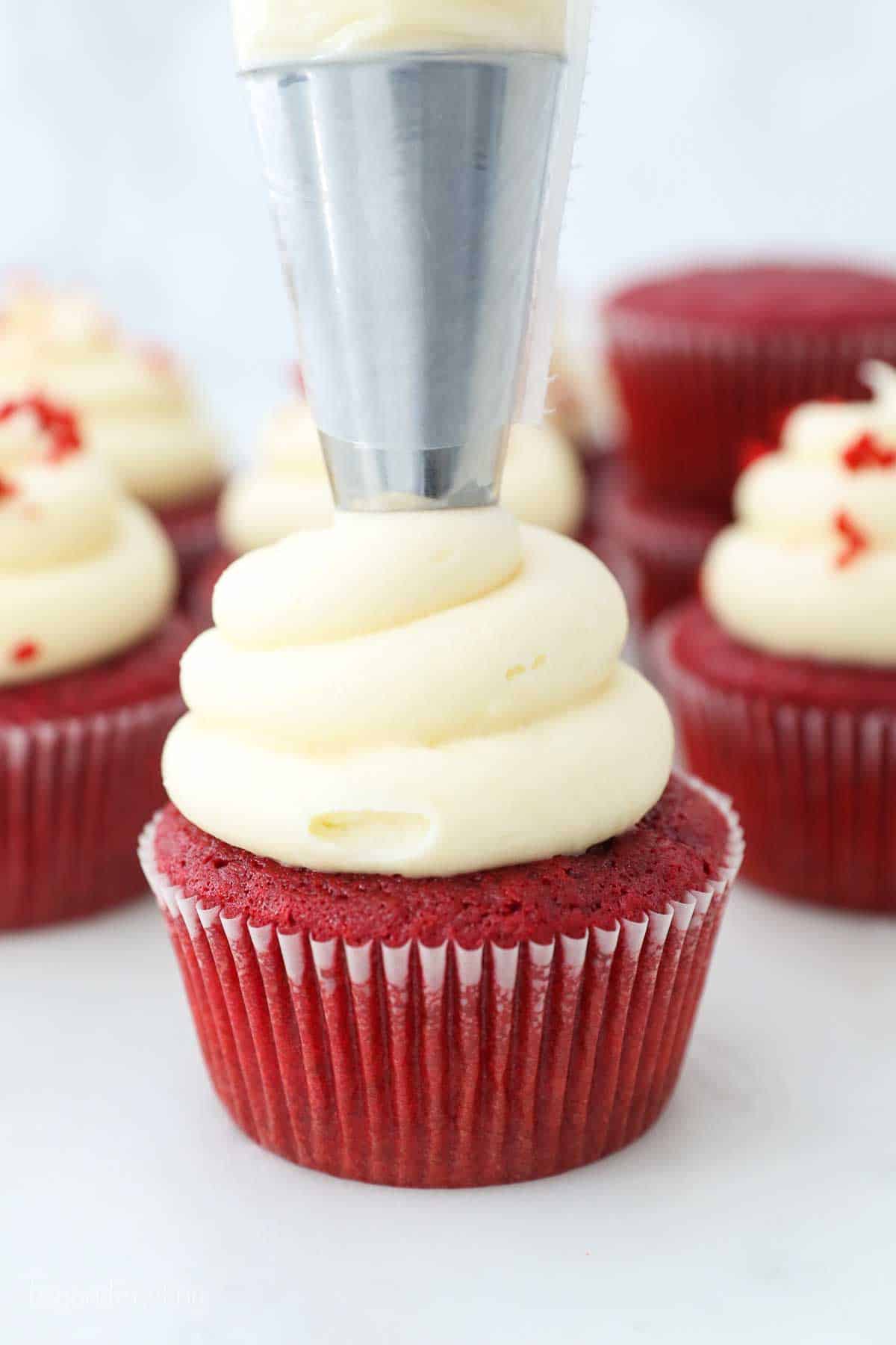 a large piping bag frosting a red cupcake