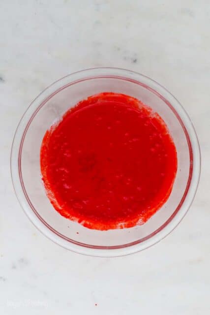 overhead view of glass mixing bowl with red cake batter