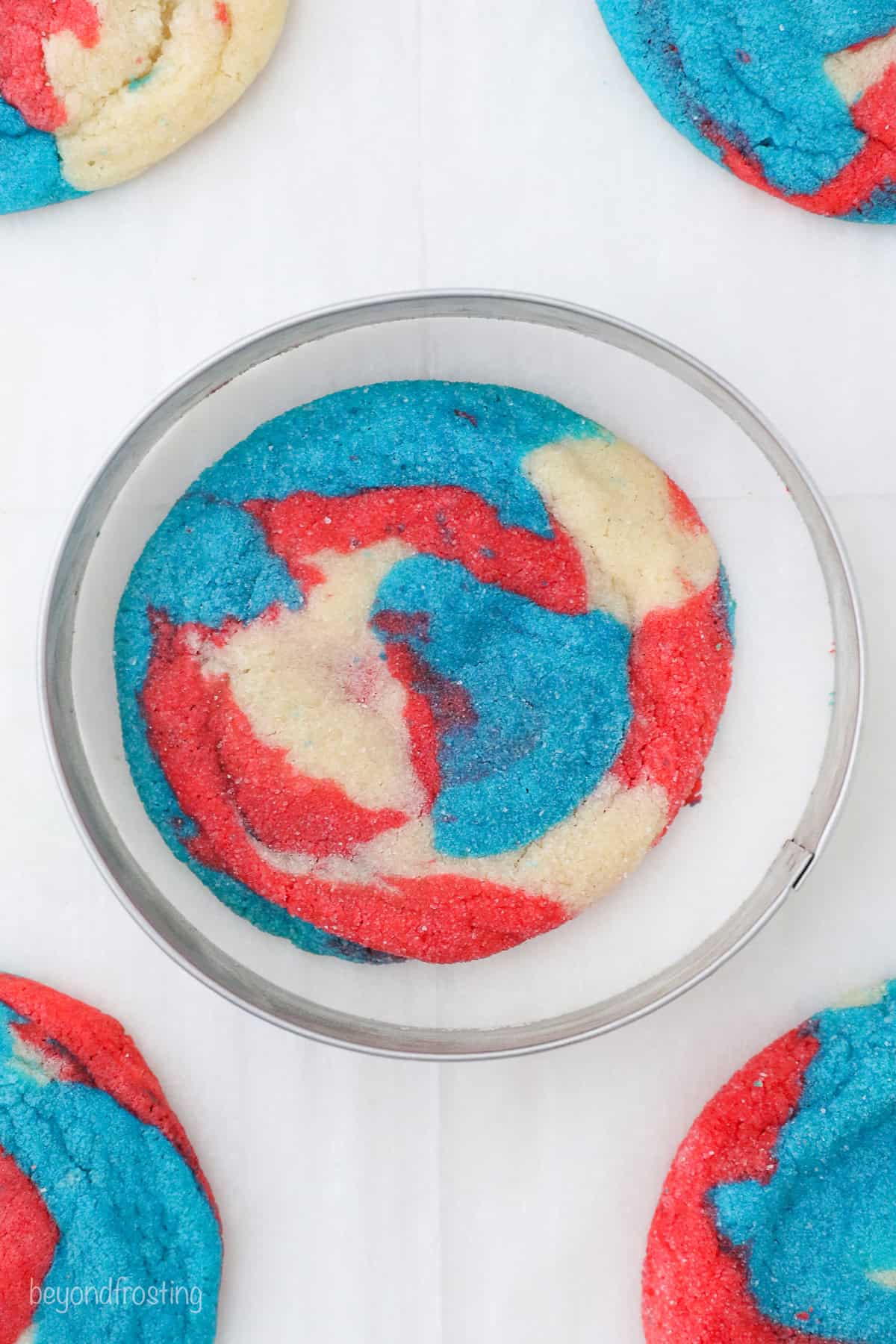 Overhead view of a baked tye-dyed patriotic cookie surrounded by a circle cookie cutter.
