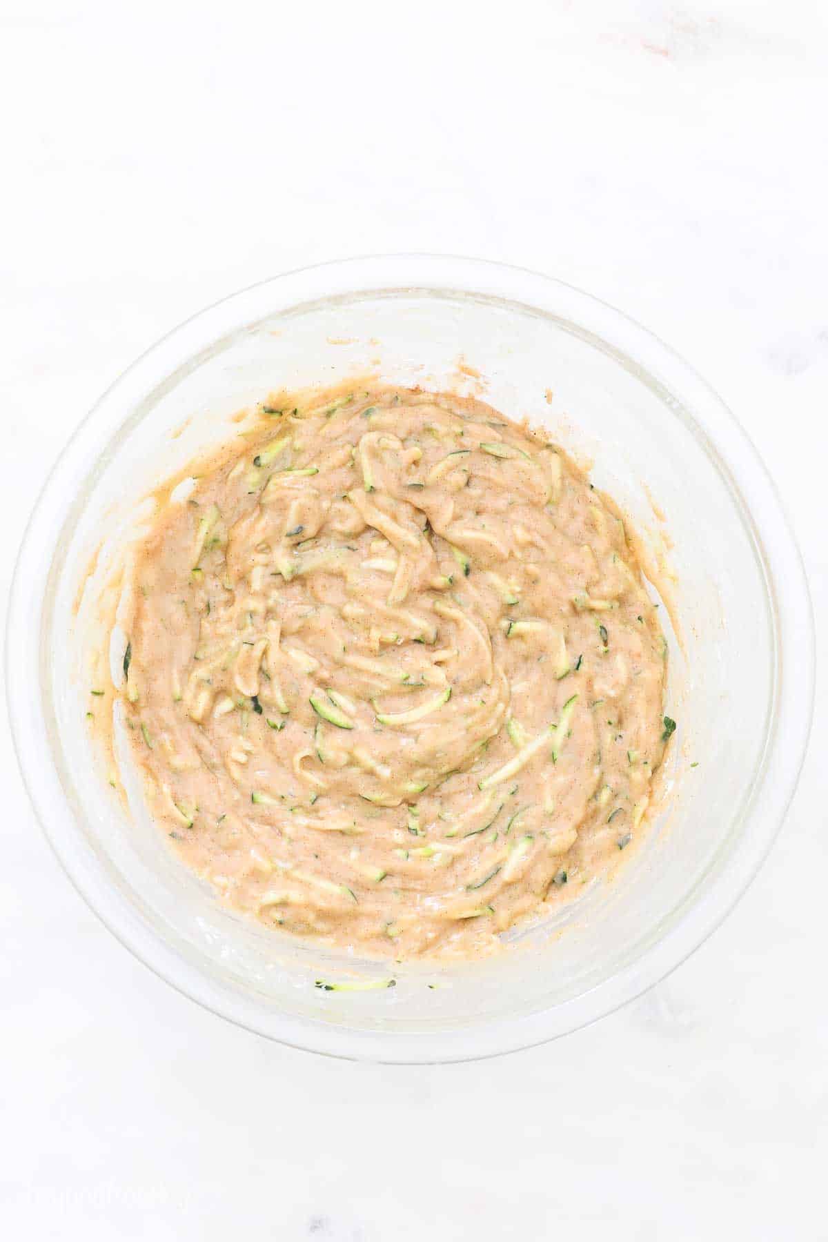 Zucchini bread batter in a glass mixing bowl.