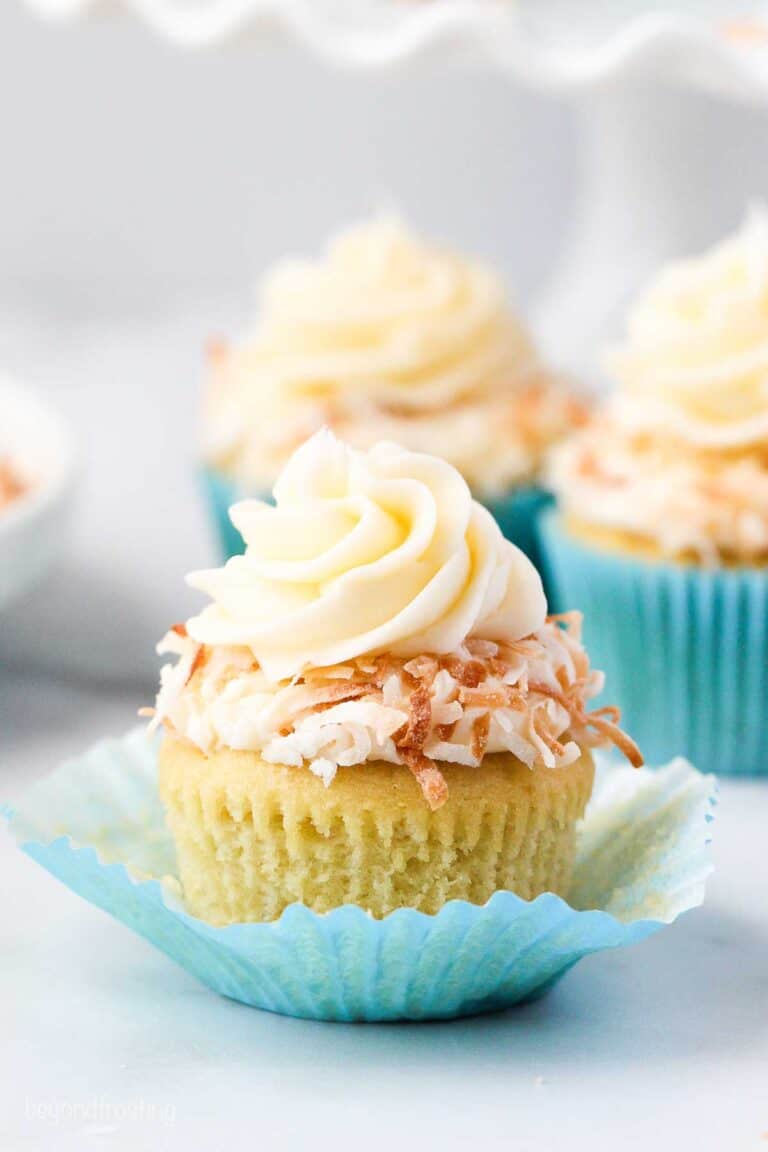 A coconut cupcake topped with cream cheese frosting and toasted coconut