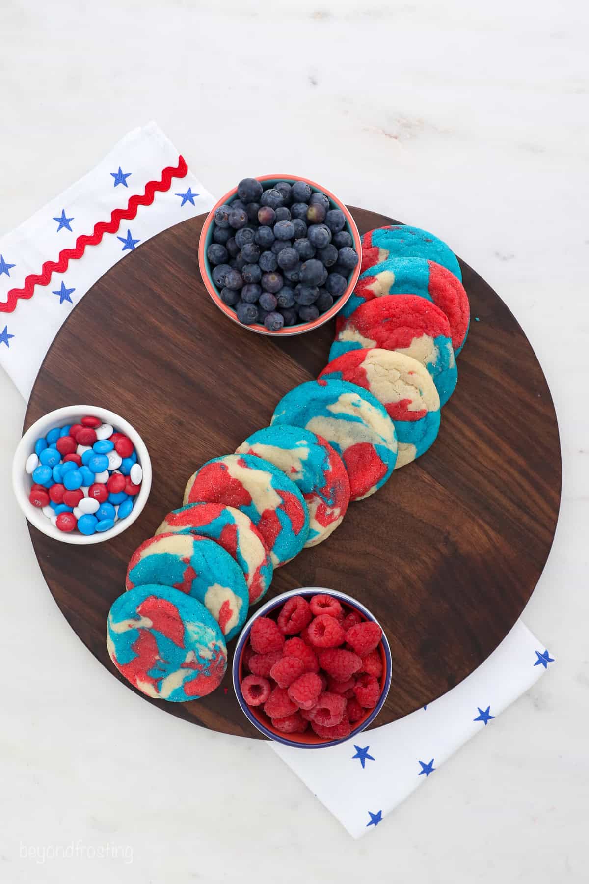 Overhead view of a partially assembled 4th of July dessert board with red, white, and blue themed nibbles.
