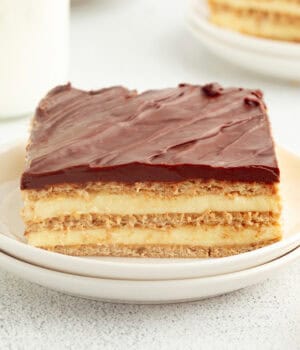 A slice of no-bake eclair cake on a plate, showing the creamy layers.