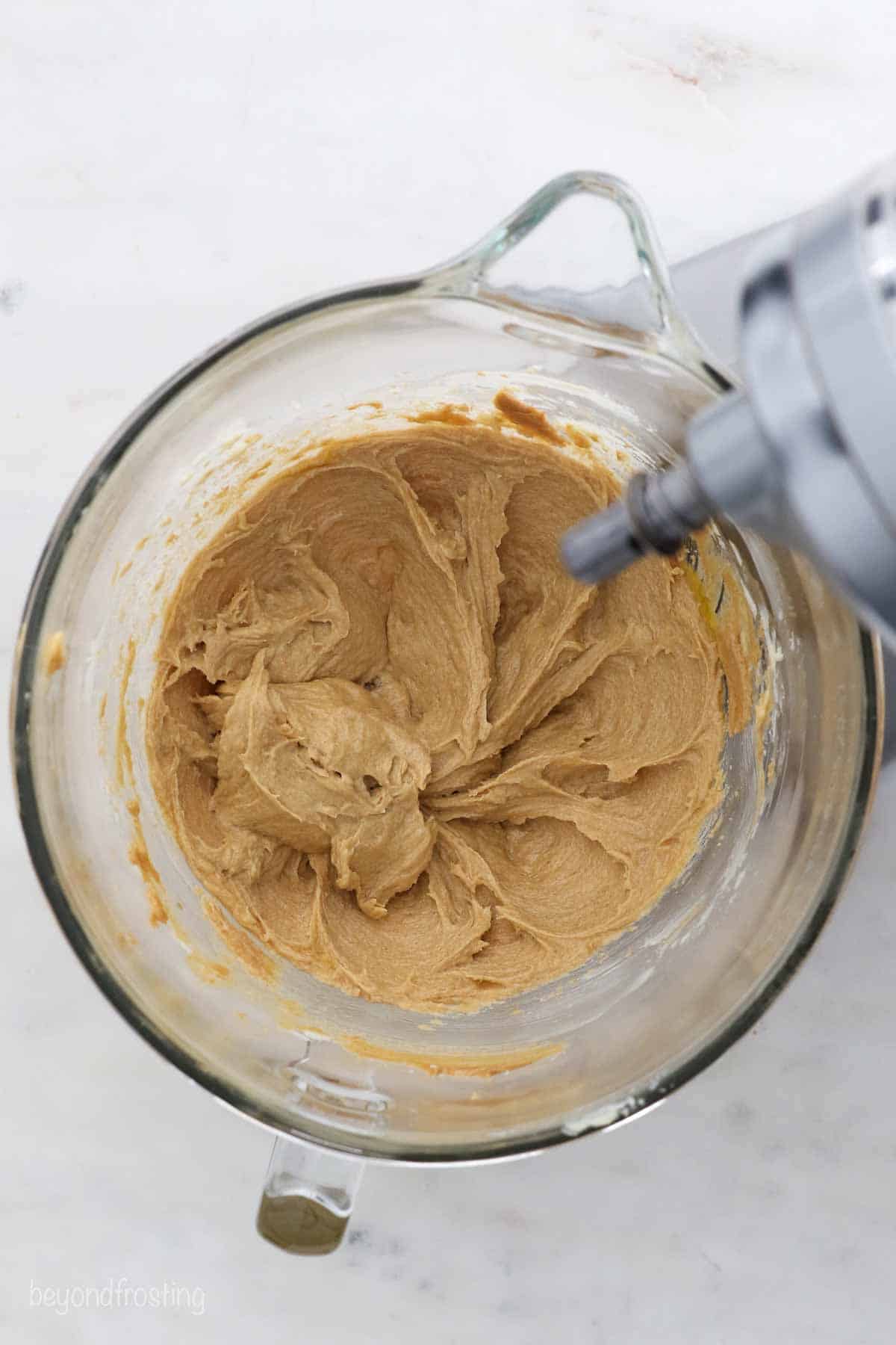 Peanut butter being creamed with sugar in a mixing bowl
