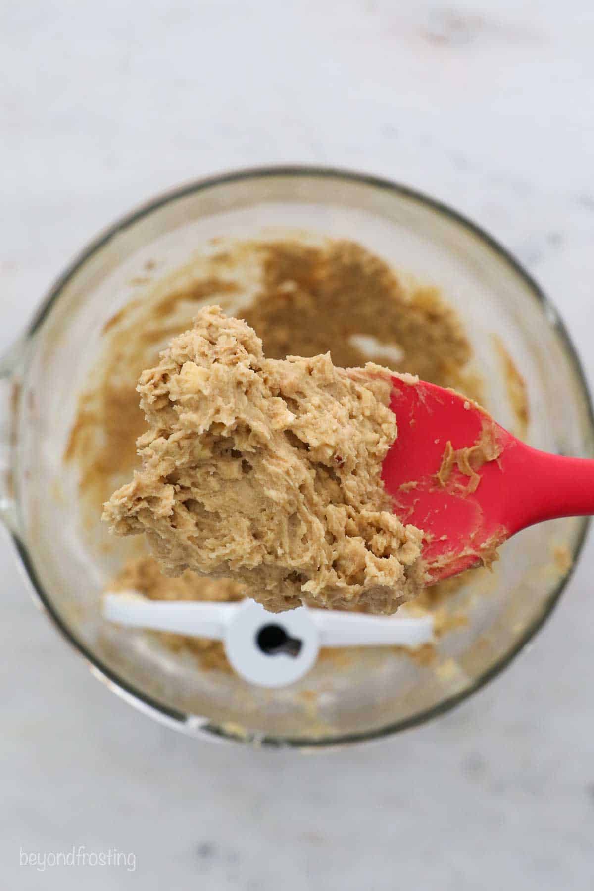 Oatmeal cookie dough on a red spatula over a mixing bowl