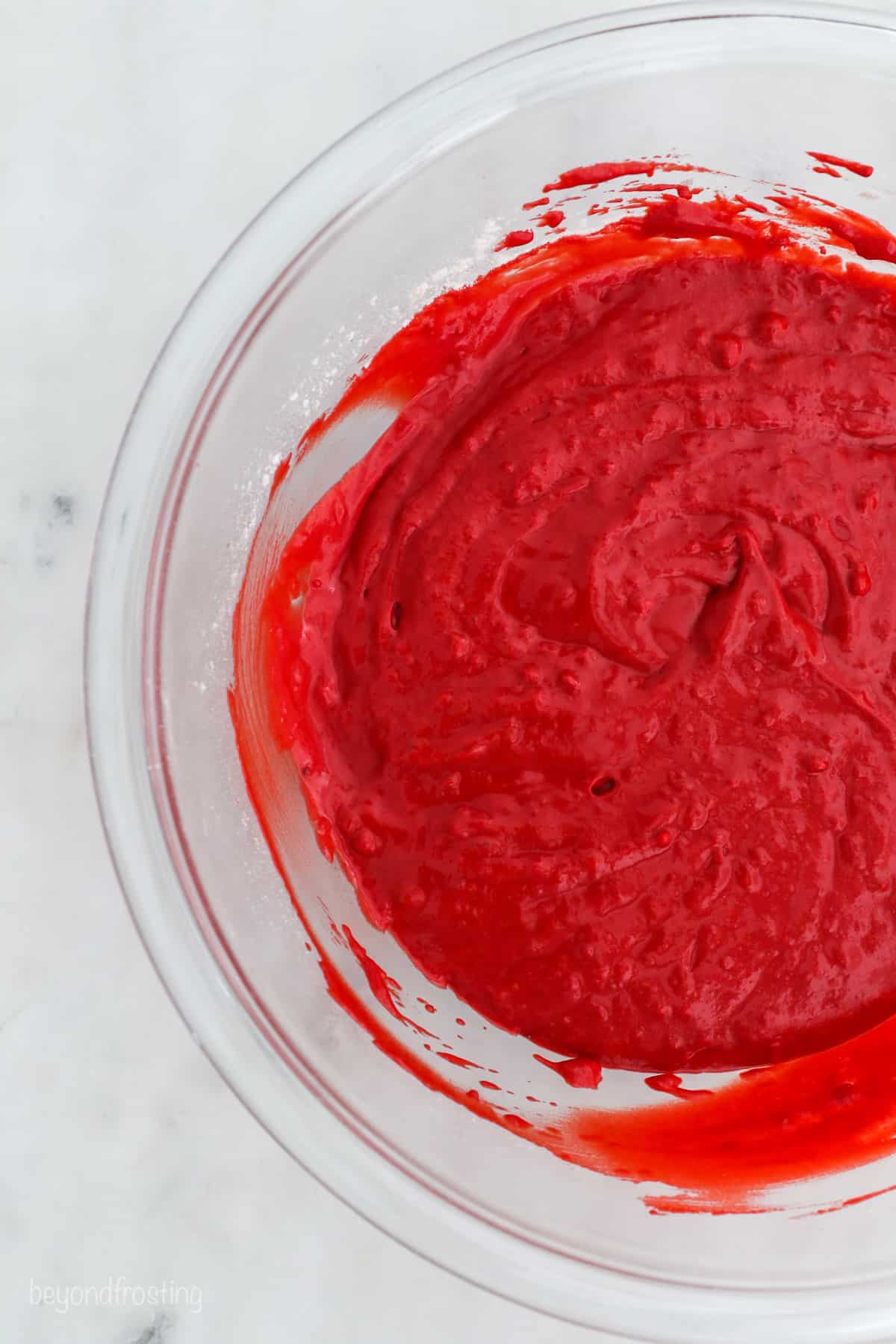 Close up of red velvet cake batter in a glass bowl.
