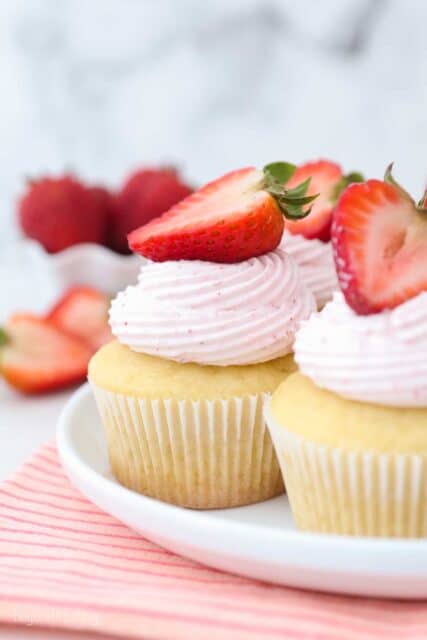 a cupcake frosted with strawberry frosting and topped with a sliced strawberry