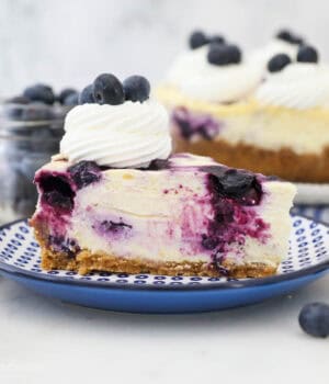 A close up of a slice of blueberry cheesecake on a blue polka dot plate