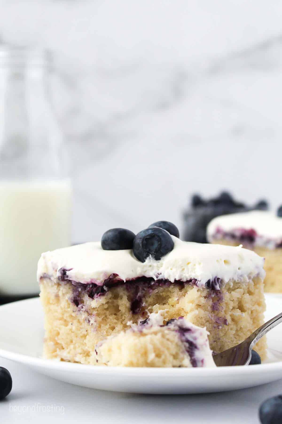 a slice of cake on a white plate garnished with blueberries
