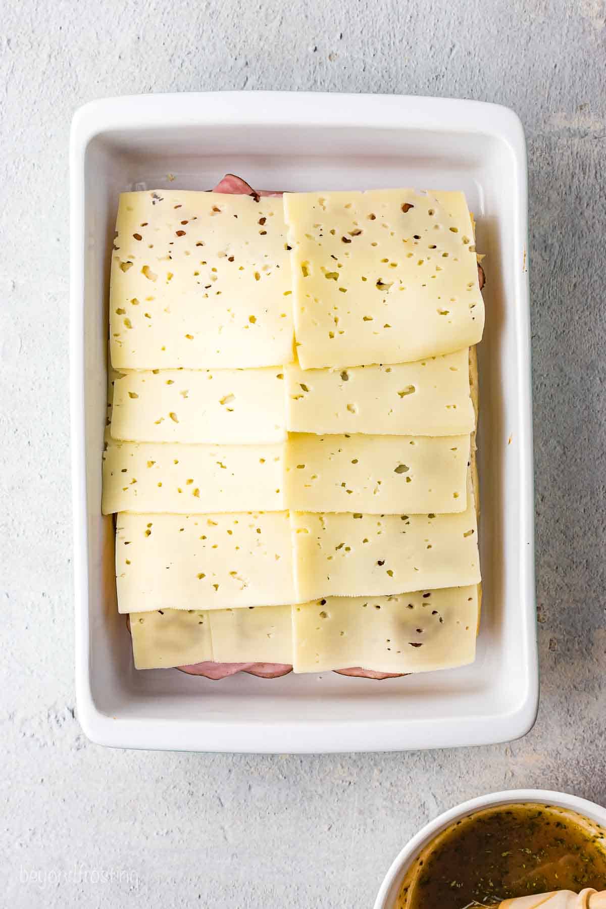 Cheese layered on top of the ham, pineapple, and Hawaiian rolls.