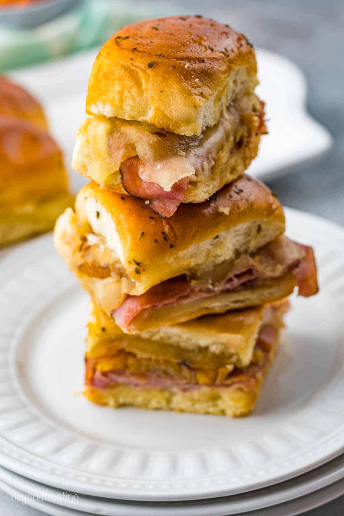 A stack of Ham and Cheese sliders on a plate.