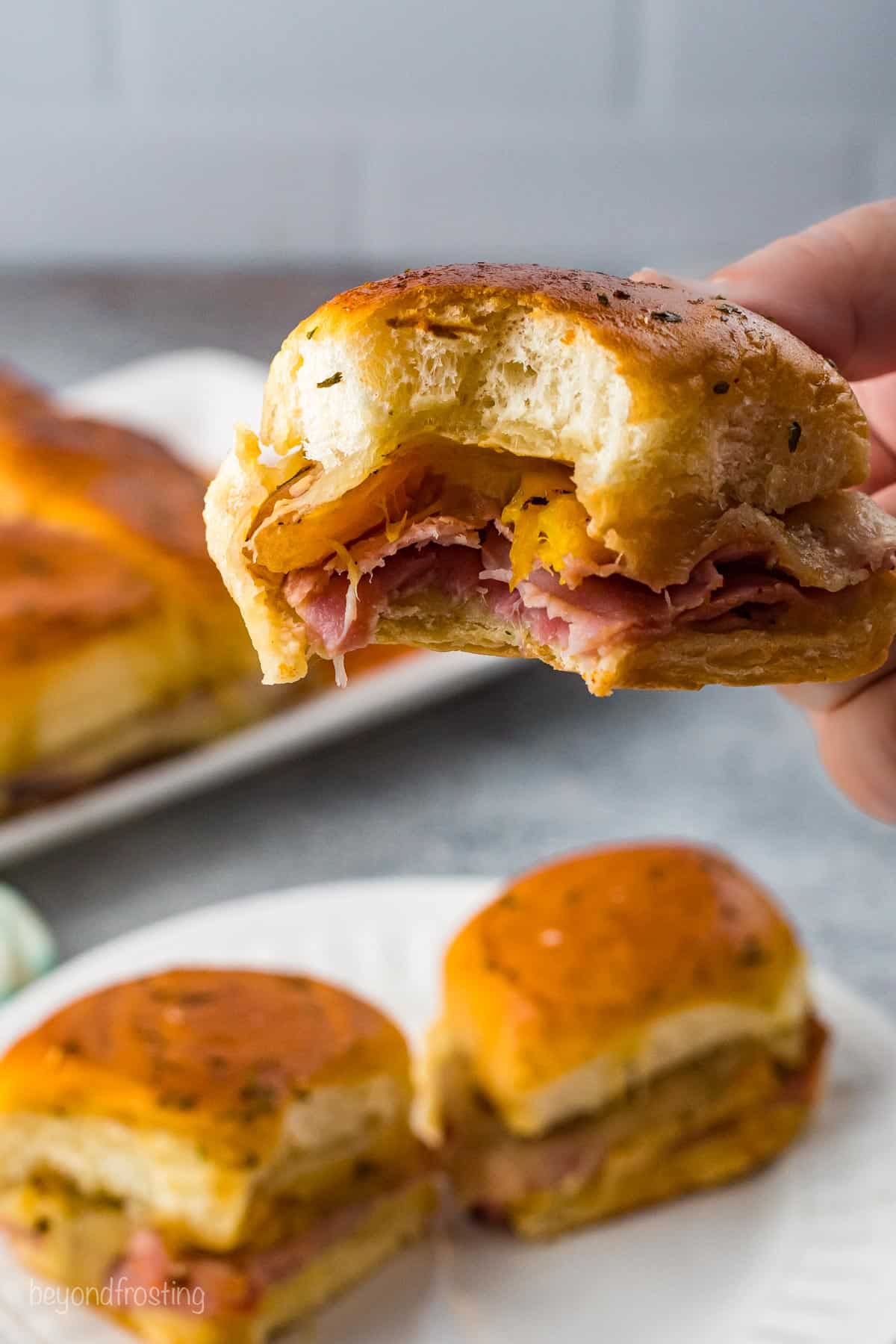 A Ham and Cheese Slider with a bite taken out, showing all of the cheese and ham on the inside.
