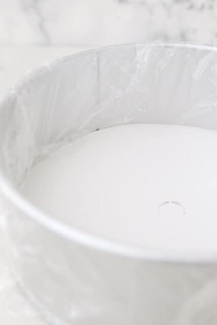 a springform pan lined with plastic wrap and a cake board in the bottom