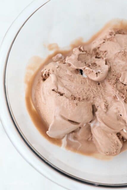 a close up shot of a a glass mixing bowl with softened ice cream