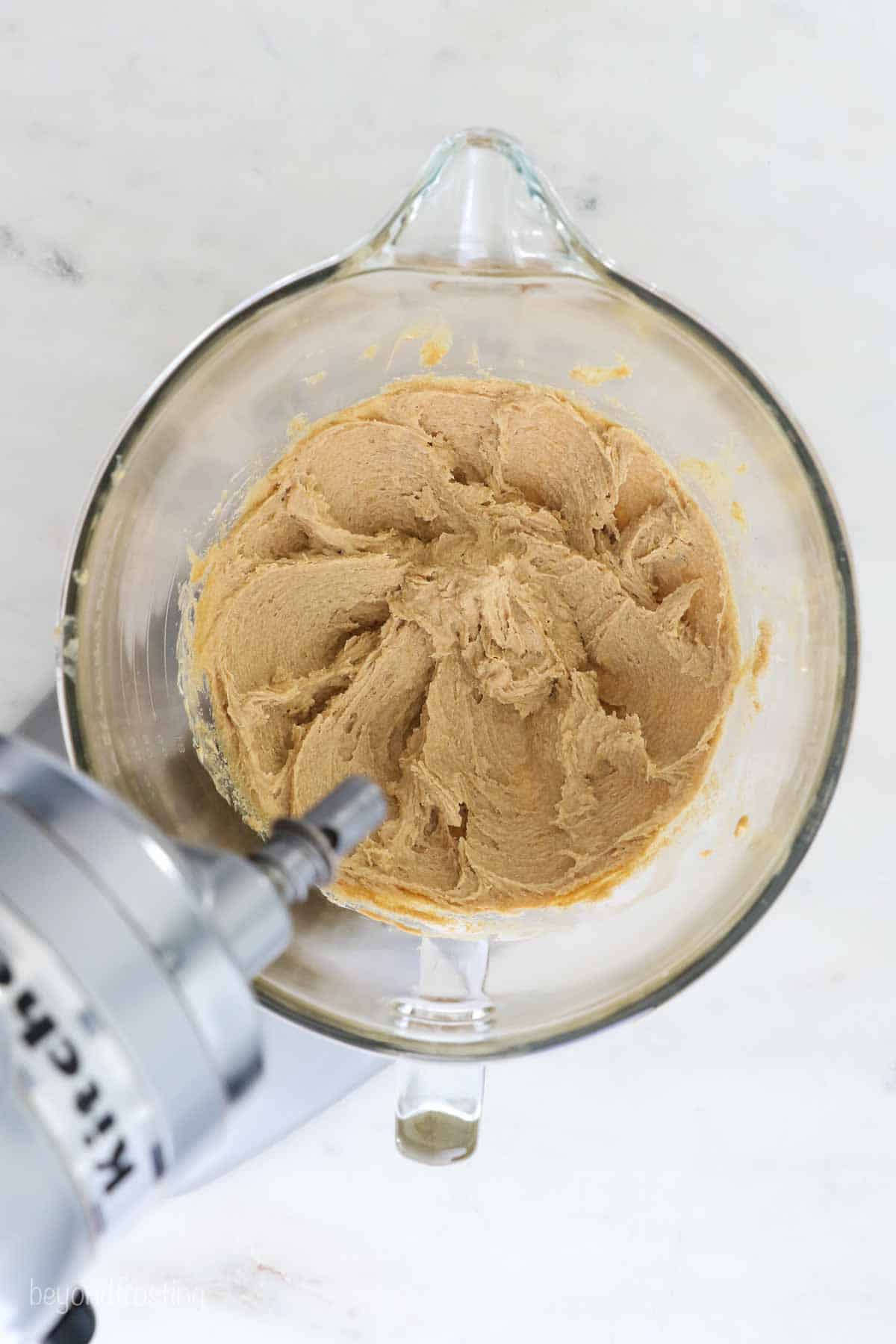 A mixing bowl showing the peanut butter and butter being mixed together.