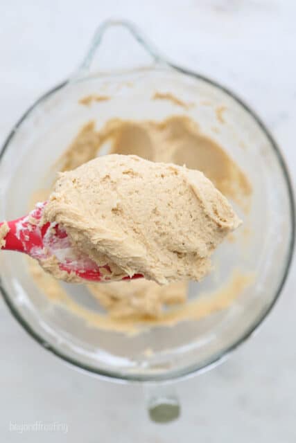 A Bird's Eye View of a glass mixing bowl, a red spatula and a close up of some whipped peanut butter
