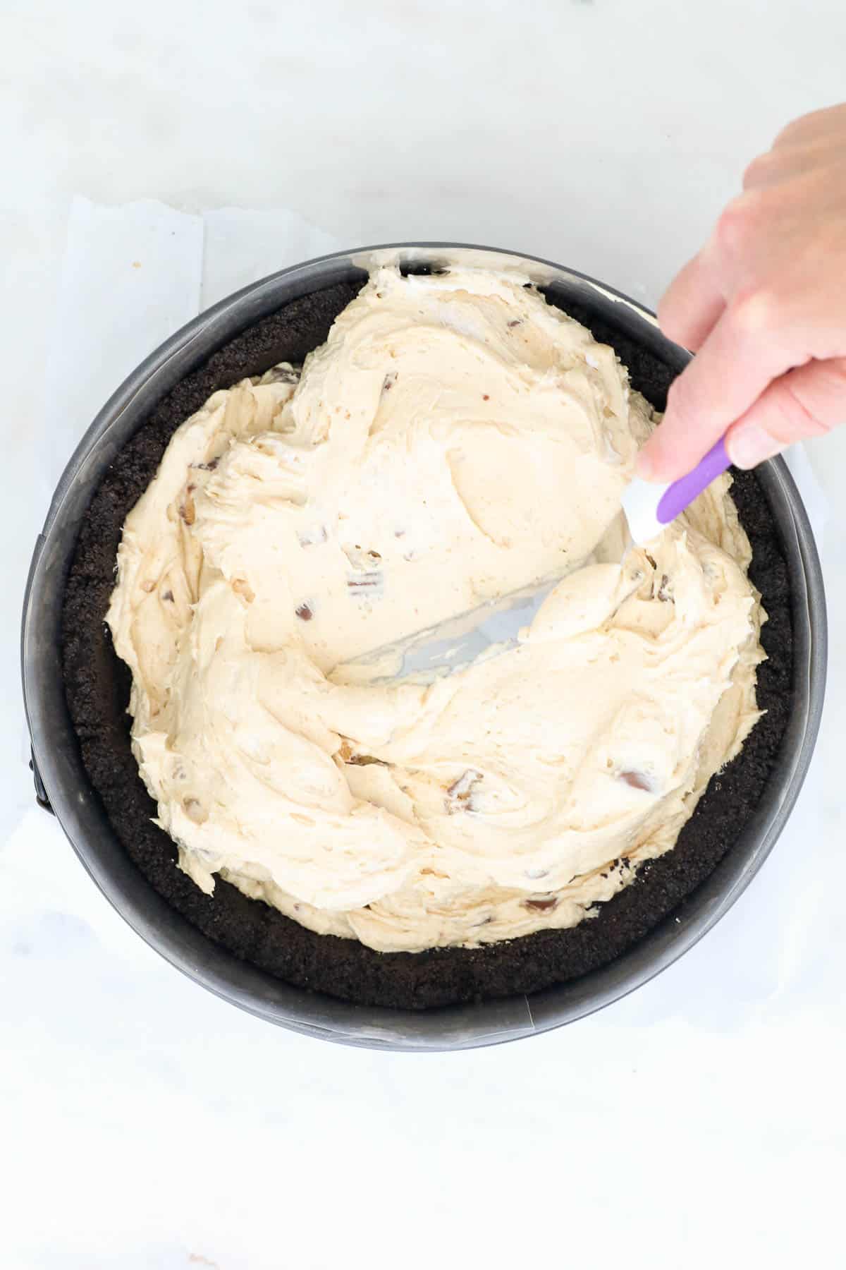 A Bird's Eye View of an an angled spatula spreading cheesecake filling in a springform pan