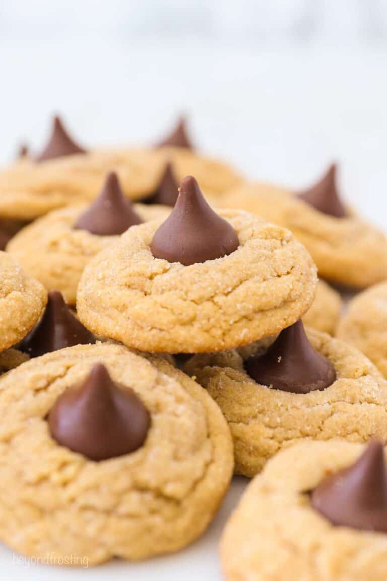 A batch of Peanut Butter Blossoms with some stacked on top of each other.