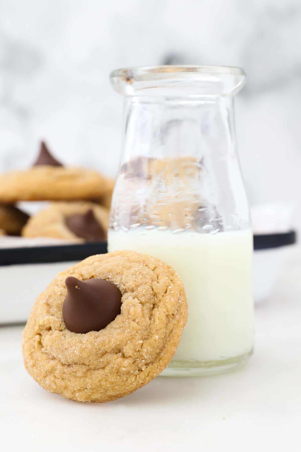 A Peanut Butter Kiss Cookie leaned up against a glass of milk.