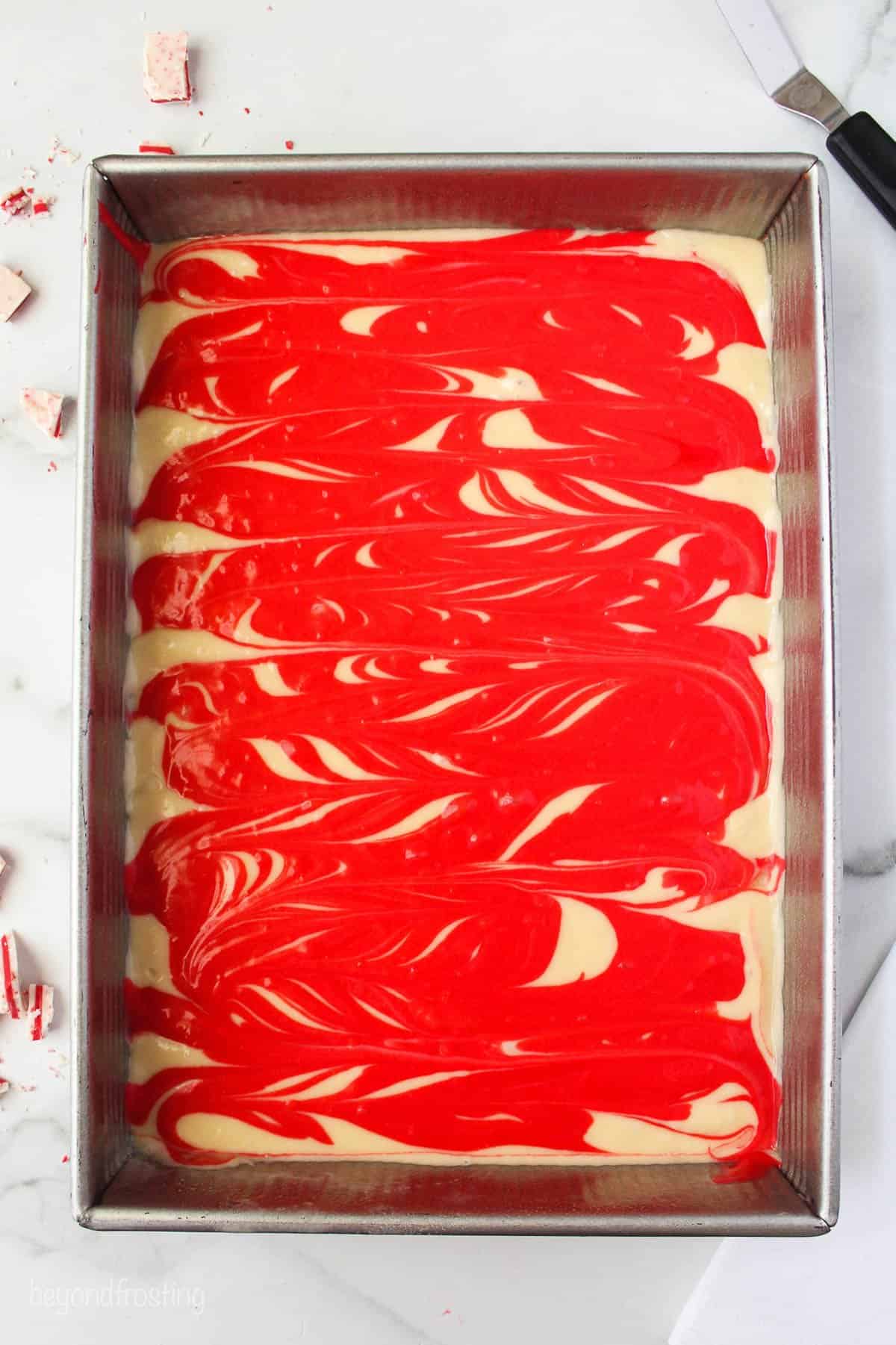 red and white cake batters swirled together in a cake pan