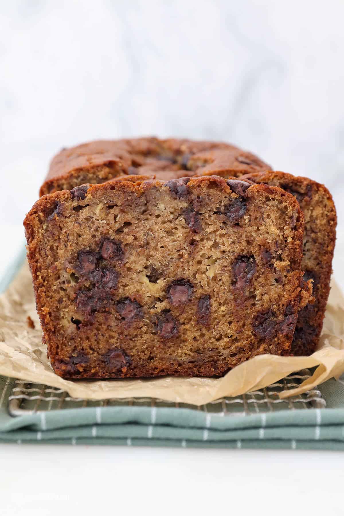 Sliced chocolate chip banana bread on a piece of brown parchment paper.