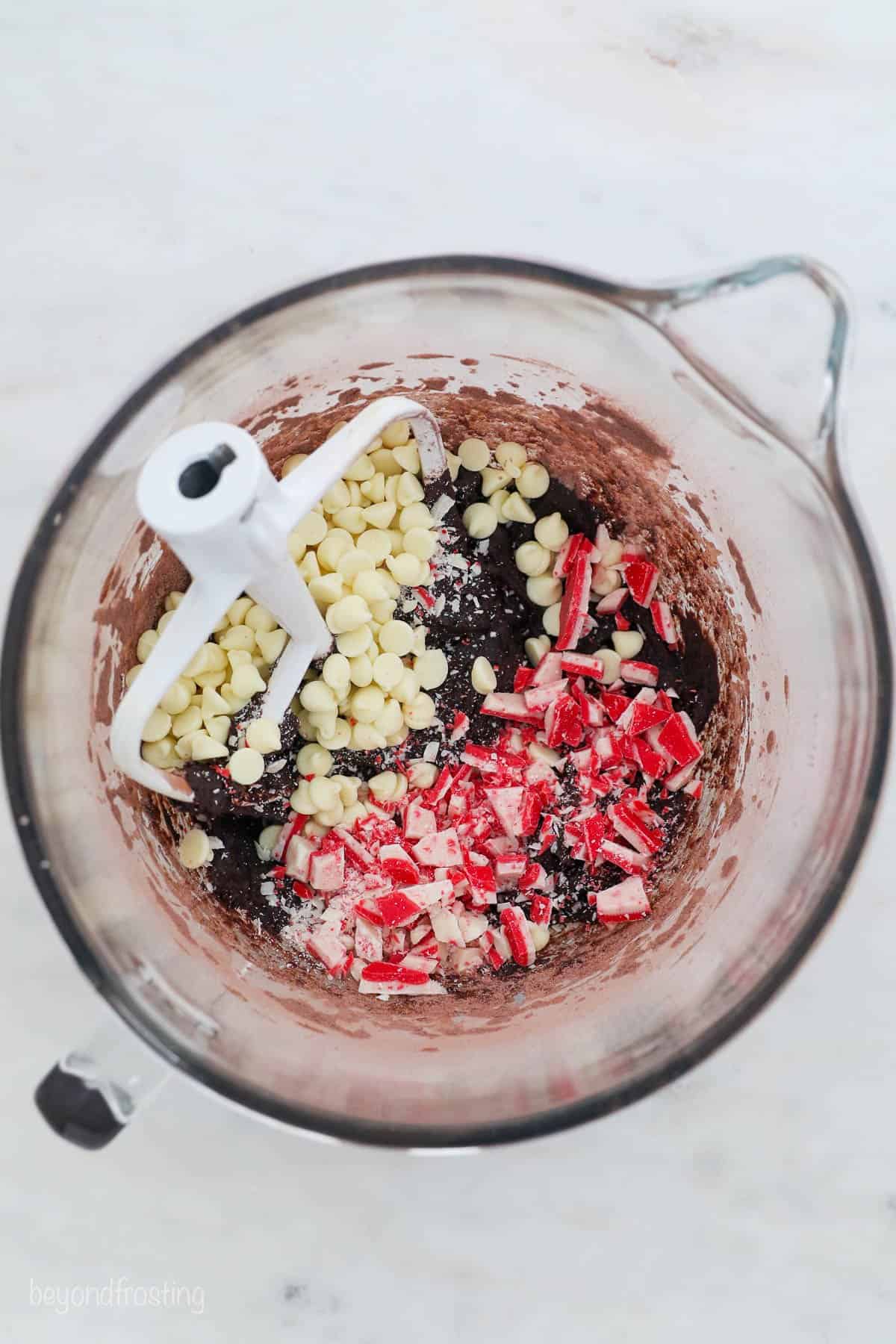 White chocolate chips and Andes Peppermint Crunch added to a bowl of chocolate cookie dough.