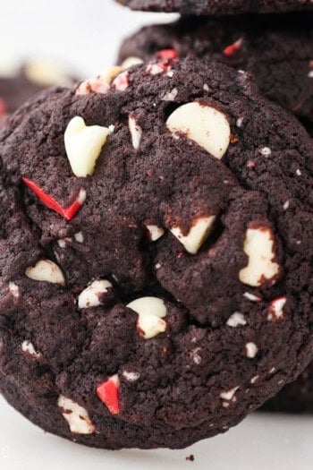 Close up of a double chocolate peppermint cookie leaning against a stack of cookies.