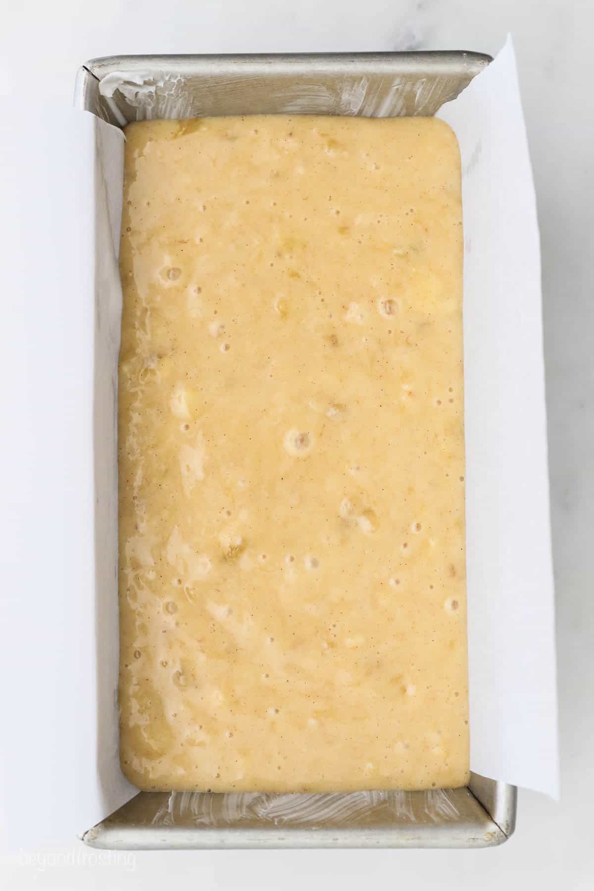 The batter poured into a parchment-lined loaf pan.