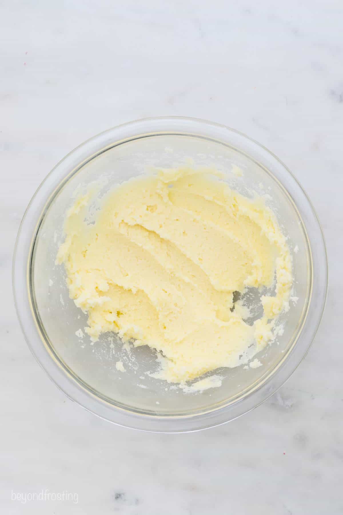This easy edible sugar cookie dough is egg-free and made with heat-treated flour. It's safe to eat and just as good as the baked version! Overhead view of a glass mixing bowl with creamed butter and sugar.