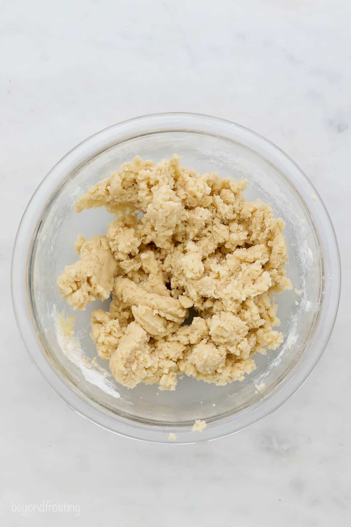 This easy edible sugar cookie dough is egg-free and made with heat-treated flour. It's safe to eat and just as good as the baked version! Overhead view of a glass mixing bowl with sugar cookie dough.