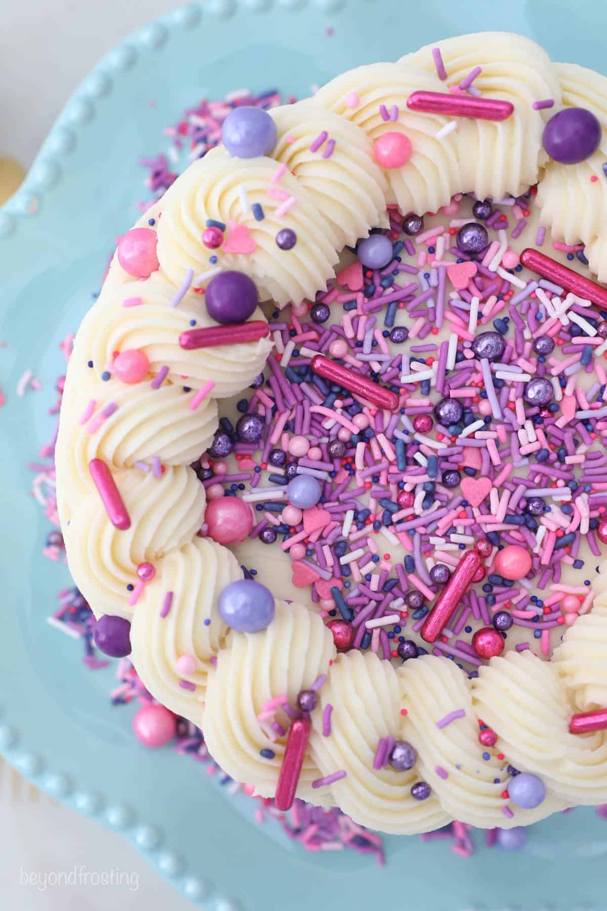 overhead view of a decorated cake with pink and purple sprinkles