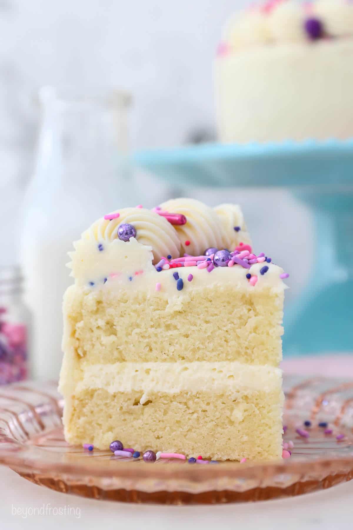 a small slice of vanilla cake with sprinkles on a pink glass plate