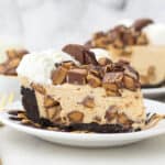 A side view of a slice pf peanut butter cheesecake loaded with Reese's peanut butter cups
