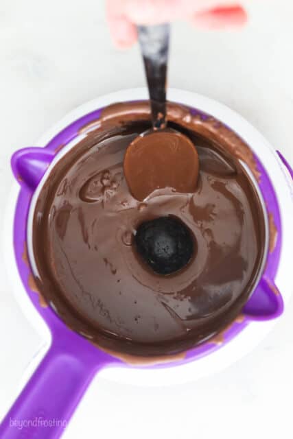 Using a spoon to dip the truffles into the melted chocolate.