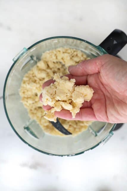 a hand holding some pie dough being pressed together