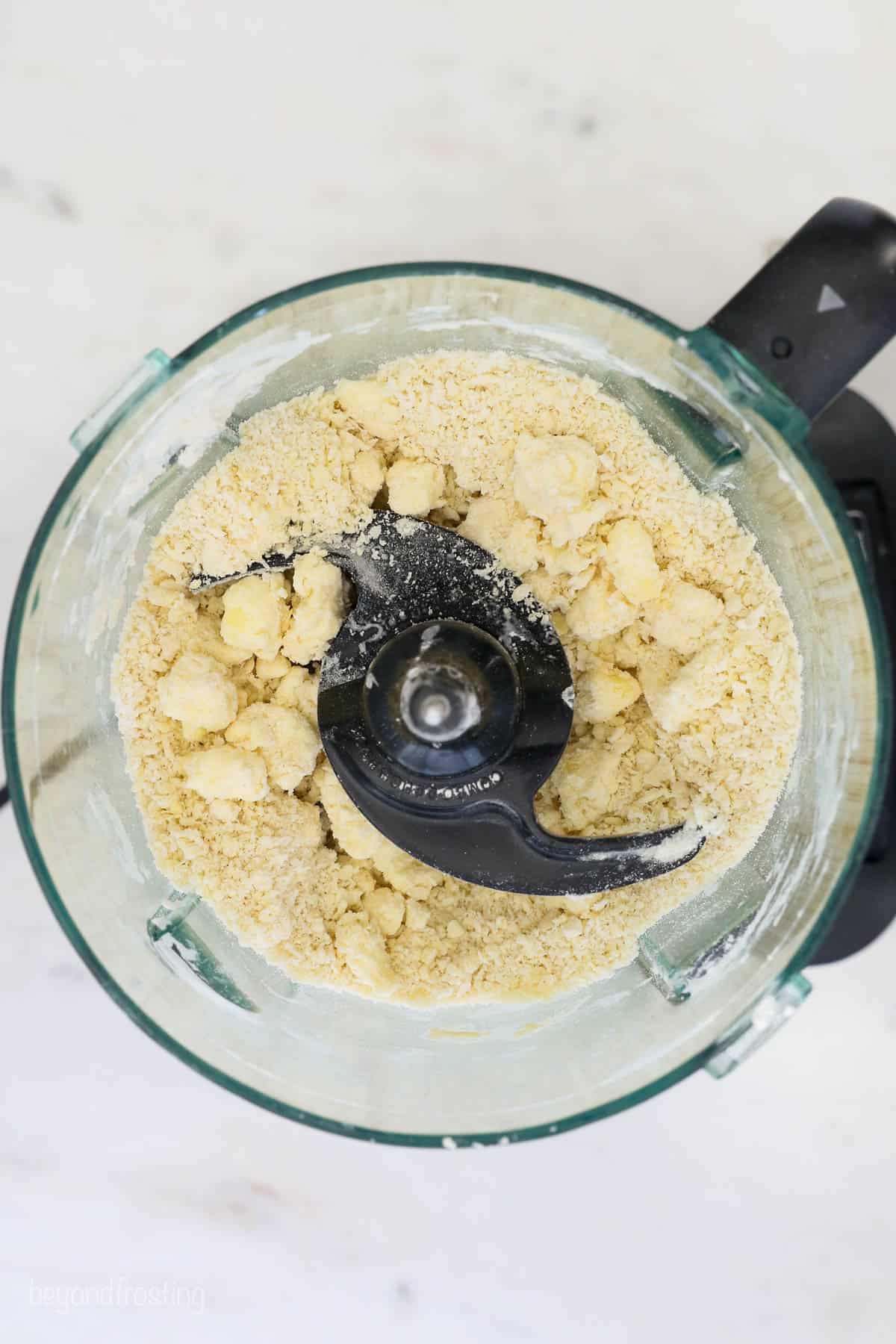 An egg and vinegar being mixed with the rest of the dough ingredients inside of a food processor